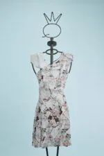 Abito estivo a maniche asimmetriche con stampa floreale su un manichino, sfondo azzurro. Design elegante e moderno, ideale per occasioni casual e primaverili.