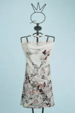 Abito estivo con stampa floreale su manichino, caratterizzato da spalline sottili e un design leggero, su sfondo blu chiaro. Perfetto per occasioni casual e giornate soleggiate.