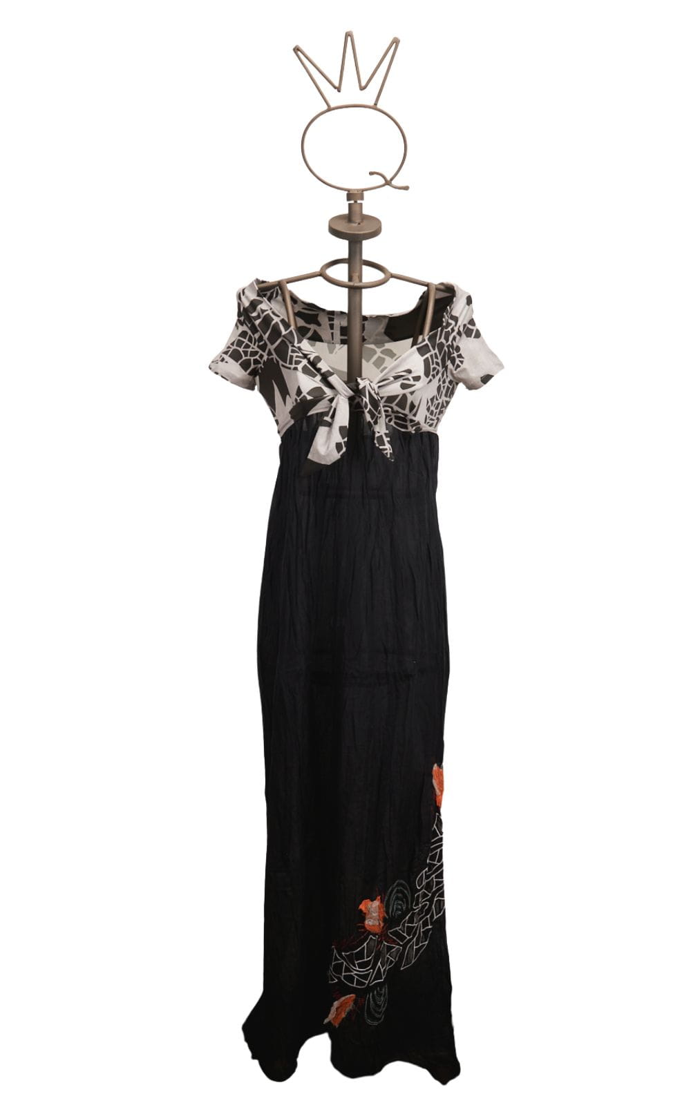 13SSNB423_a Abito lungo da donna con maniche corte e scollatura a V, caratterizzato da un top in bianco e nero con motivo floreale e una gonna nera con ricami colorati. Esposto su un manichino con una base decorativa.