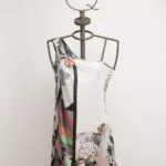 Abito senza maniche con design astratto e colori vivaci, esposto su un manichino in metallo con una corona decorativa. Ideale per occasioni estive e look informali.