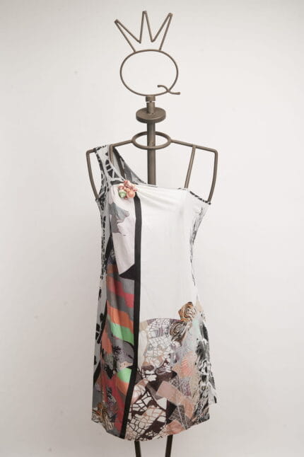 Abito senza maniche con design astratto e colori vivaci, esposto su un manichino in metallo con una corona decorativa. Ideale per occasioni estive e look informali.
