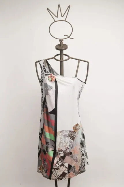 Abito senza maniche con design astratto e colori vivaci, esposto su un manichino in metallo con una corona decorativa. Ideale per occasioni estive e look informali.