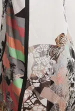 Dettaglio di un abito con un design astratto e colorato, caratterizzato da motivi geometrici e floreali su uno sfondo bianco.