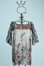 Abito estivo con maniche a sbuffo, caratterizzato da un design multicolore e fantasie floreali, esposto su un manichino su sfondo azzurro.