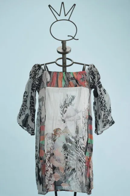 Abito estivo con maniche a sbuffo, caratterizzato da un design multicolore e fantasie floreali, esposto su un manichino su sfondo azzurro.