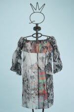 Lightweight and colorful dress on mannequin, featuring an off-shoulder design and puff sleeves, with abstract patterns in shades of black, white and bright colors on a light blue background.