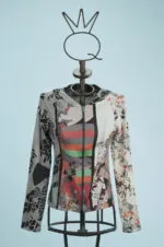 Giacca con cappuccio a maniche lunghe, caratterizzata da un design astratto e colori vivaci, esposta su un manichino con base metallica. Sfondo azzurro per un contrasto accattivante.