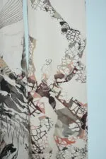 Detail of a fabric with an abstract pattern combining natural elements and graphics, featuring muted shades of beige, brown and blue. Ideal for clothing or interior decoration.