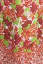 Détail d'un tissu floral avec des roses rouges et vertes sur fond blanc, accompagné d'un motif géométrique rouge. Idéal pour les tenues d'été et les occasions spéciales.