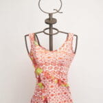 Top à manches courtes pour femme avec motif floral rouge et détails verts, présenté sur un mannequin à support métallique. Design moderne et frais, idéal pour la saison estivale. 