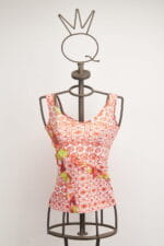 Top à manches courtes pour femme avec motif floral rouge et détails verts, présenté sur un mannequin à support métallique. Design moderne et frais, idéal pour la saison estivale.