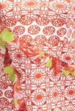 Détail d'un tissu à motif floral et géométrique dans les tons rouge et orange, idéal pour les vêtements d'été ou les accessoires de mode.