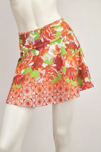 Gonna corta a fiori rossi e verdi su manichino, ideale per la stagione estiva, con un design vivace e fresco.