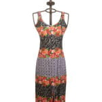 Abito lungo da donna con stampa floreale e motivi geometrici, presentato su un manichino. Design estivo con spalline sottili e spacco frontale, perfetto per occasioni casual e feste all'aperto.