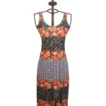Abito lungo da donna con stampa floreale e motivi geometrici, presentato su un manichino. Design estivo con spalline sottili e spacco frontale, perfetto per occasioni casual e feste all'aperto.