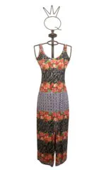 Abito lungo da donna con stampa floreale e motivi geometrici, presentato su un manichino. Design estivo con spalline sottili e spacco frontale, perfetto per occasioni casual e feste all'aperto.