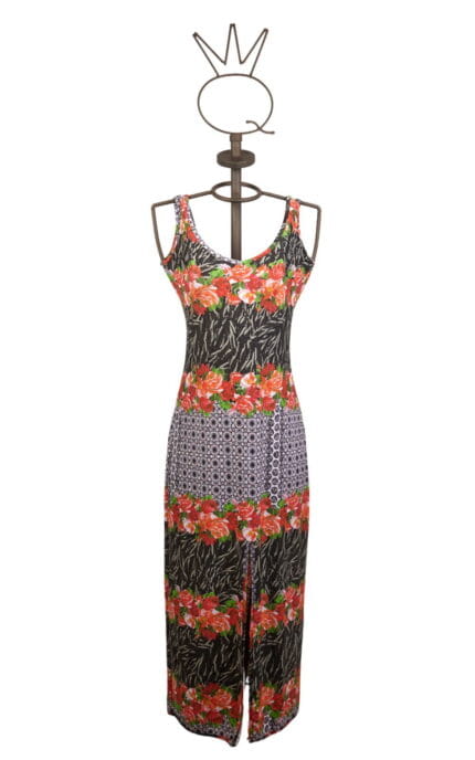 Abito lungo da donna con stampa floreale e motivi geometrici, presentato su un manichino. Design estivo con spalline sottili e spacco frontale, perfetto per occasioni casual e feste all'aperto.