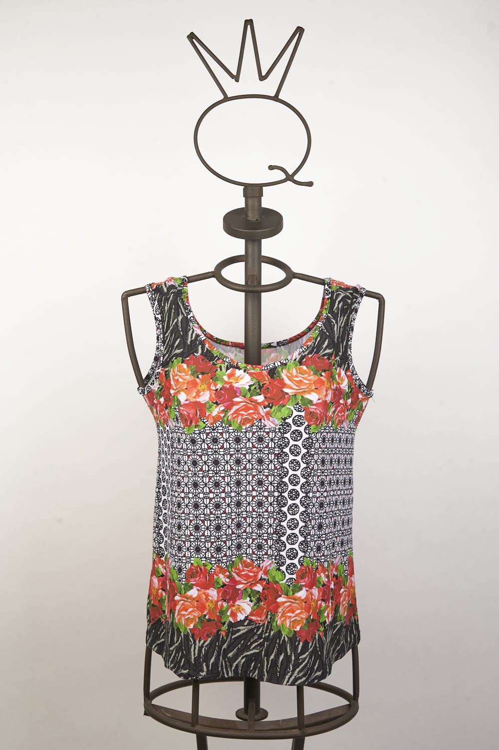 16SSNQ651_ 1 Top estivo a maniche corte con motivo floreale e geometrico, presentato su un manichino in metallo. Design vivace con fiori rossi e dettagli in bianco e nero, ideale per outfit casual e freschi.