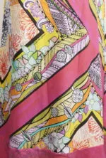 Stampa colorata e vivace su tessuto, con motivi floreali e geometrici in toni di rosa, giallo e verde, ideale per abbigliamento estivo.