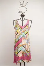 Abito estivo colorato appeso a un manichino, con motivi floreali e geometrici in tonalità vivaci di rosa, giallo e verde. Perfetto per occasioni informali e giornate estive.