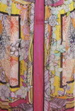 Robe colorée aux motifs floraux et géométriques, dans des tons vifs de jaune, rose et orange, idéale pour les occasions estivales. Design élégant et original avec des détails artistiques.