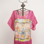 Top d'été coloré à manches courtes, avec un motif floral vivant et des détails en maille rose. Présenté sur un mannequin décoratif avec une couronne. Idéal pour les tenues d'été et les occasions décontractées.  