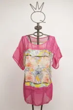 Top estivo colorato con maniche corte, caratterizzato da un motivo floreale vivace e dettagli in rete rosa. Esposto su un manichino decorativo con una corona. Ideale per outfit estivi e occasioni casual.