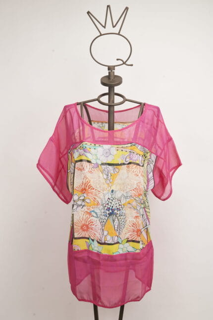 Top estivo colorato con maniche corte, caratterizzato da un motivo floreale vivace e dettagli in rete rosa. Esposto su un manichino decorativo con una corona. Ideale per outfit estivi e occasioni casual.