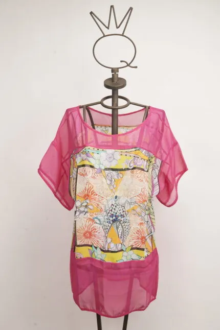 Top estivo colorato con maniche corte, caratterizzato da un motivo floreale vivace e dettagli in rete rosa. Esposto su un manichino decorativo con una corona. Ideale per outfit estivi e occasioni casual.