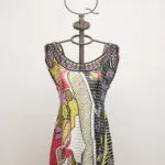 Abito estivo colorato su manichino, con motivi grafici vivaci e scollatura ampia, ideale per look casual e alla moda.