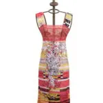 Abito colorato con motivi floreali e strisce, esposto su un manichino con una corona stilizzata in cima, ideale per la moda estiva e le occasioni speciali.