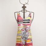 Abito estivo colorato con stampa floreale e righe, esposto su un manichino in metallo con una corona decorativa. Ideale per occasioni informali e look estivi.