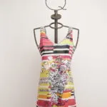 Abito estivo colorato con stampa floreale e righe, esposto su un manichino in metallo con una corona decorativa. Ideale per occasioni informali e look estivi.