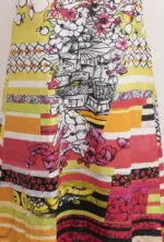 Abito lungo colorato con motivi floreali e strisce multicolori, ideale per le giornate estive. Il design presenta dettagli grafici di frutta e fiori, perfetto per uno stile vivace e fresco.