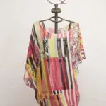 Camicia estiva in chiffon colorata, con motivi geometrici e floreali, esposta su un manichino artistico. Perfetta per look casual e freschi.