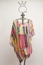 Camicia estiva in chiffon colorata, con motivi geometrici e floreali, esposta su un manichino artistico. Perfetta per look casual e freschi.