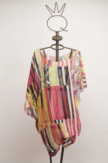 Camicia estiva in chiffon colorata, con motivi geometrici e floreali, esposta su un manichino artistico. Perfetta per look casual e freschi.