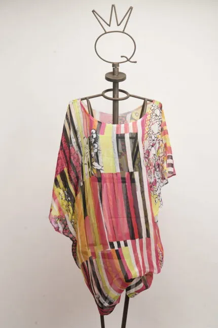 Camicia estiva in chiffon colorata, con motivi geometrici e floreali, esposta su un manichino artistico. Perfetta per look casual e freschi.