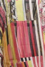 Dettaglio di un tessuto leggero e colorato con strisce rosa, gialle e nere, arricchito da motivi floreali e grafismi. Ideale per abbigliamento estivo e accessori di moda.