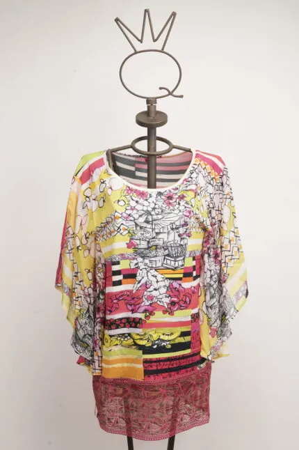 Maglietta colorata a maniche larghe esposta su un manichino, caratterizzata da motivi floreali e strisce vivaci, ideale per un look estivo e casual.