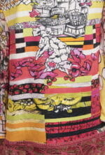Dettaglio di una camicia colorata con motivi floreali e fruttati, caratterizzata da strisce vivaci in tonalità rosa, giallo e nero. Ideale per look estivi e freschi.