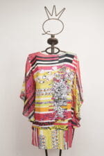 Abito estivo multicolore con maniche ampie, caratterizzato da una combinazione di strisce e motivi floreali, esposto su un manichino in un ambiente neutro. Ideale per look casual e freschi.