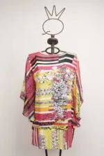 Abito estivo multicolore con maniche ampie, caratterizzato da una combinazione di strisce e motivi floreali, esposto su un manichino in un ambiente neutro. Ideale per look casual e freschi.