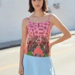 Modella in posa con top colorato e gonna azzurra, sfondo urbano, stile estivo e fresco, ideale per moda giovane.