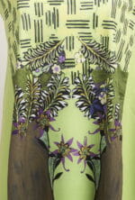 T-shirt vert clair au design coloré avec des motifs floraux et des feuilles, avec des détails artistiques qui rappellent la nature.