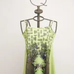 Abito verde chiaro con spalline sottili e stampa floreale, esposto su un manichino con un design moderno. Ideale per occasioni estive e casual.