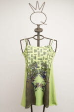 Robe vert clair à fines bretelles et imprimé floral, présentée sur un mannequin au design moderne. Idéale pour l'été et les occasions décontractées.