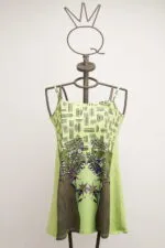 Light green dress with thin straps and floral print, displayed on a mannequin with a modern design. Ideal for summer and casual occasions.