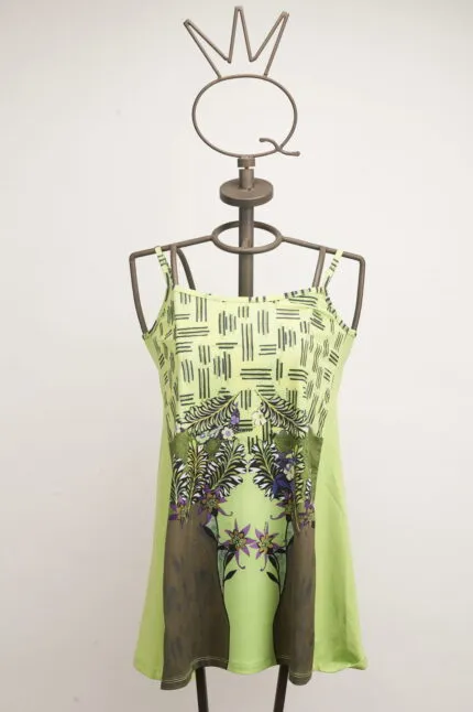 Abito verde chiaro con spalline sottili e stampa floreale, esposto su un manichino con un design moderno. Ideale per occasioni estive e casual.