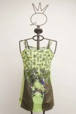 Light green dress with floral and geometric designs, displayed on a metal mannequin. Original design, ideal for the summer season.